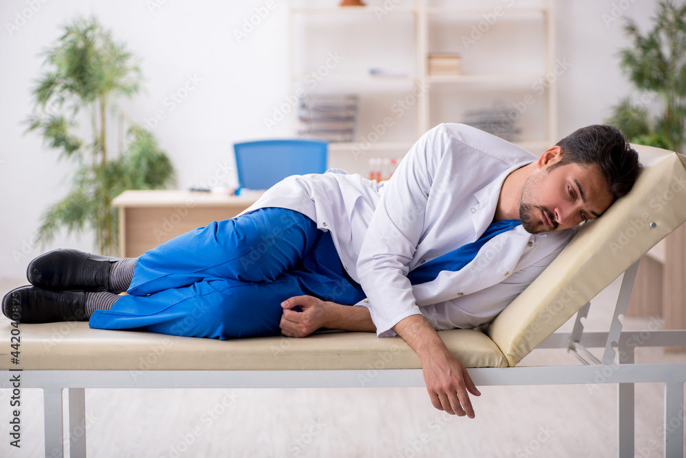 Tired young male doctor lying on the couch at the hospital Tired young male doctor lying on the couch at the hospital