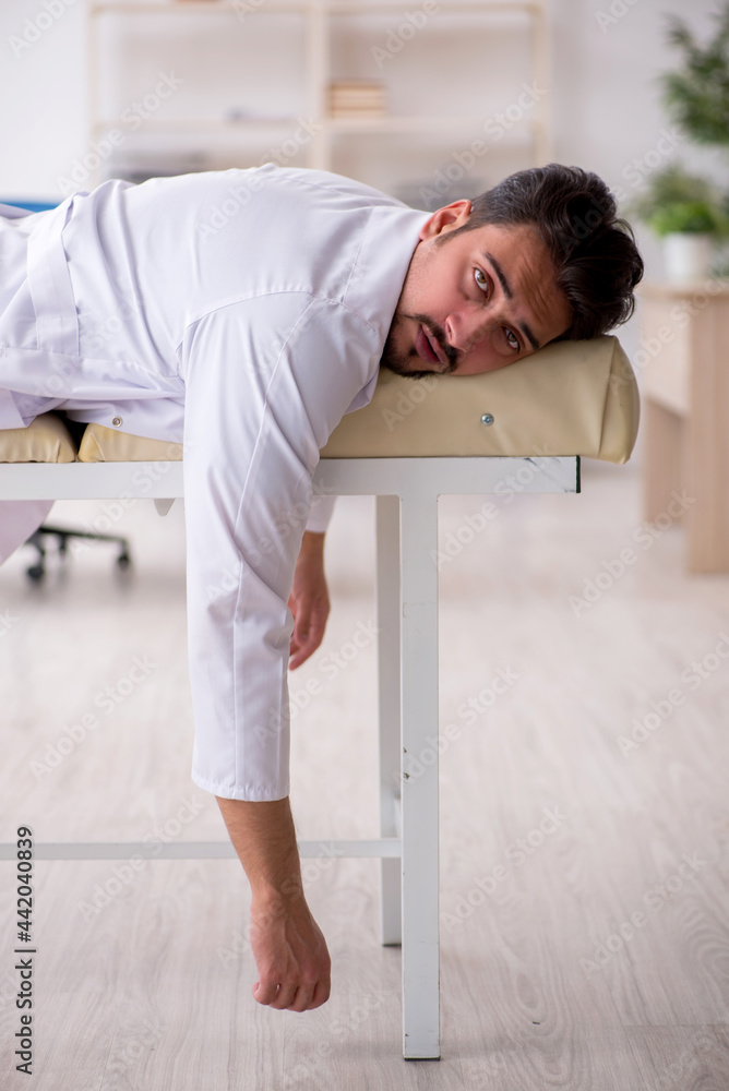 Tired young male doctor lying on the couch at the hospital Tired young male doctor lying on the couch at the hospital