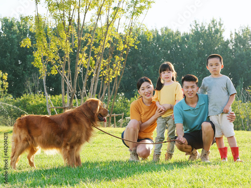 Happy family of four and pet dog in the park