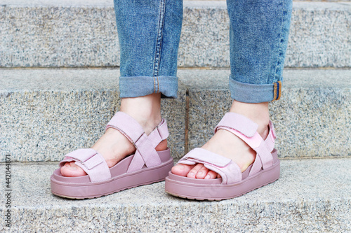 Female feet in pink sandals on on concrete staircase background close-up. © TATIANA