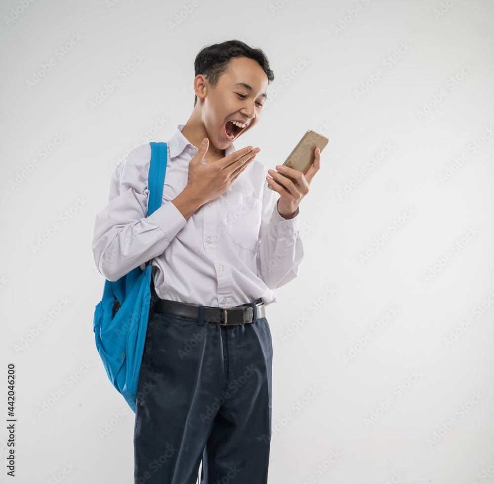 a boy wearing a junior high school uniform holding a cellphone with a surprised expression and gesture when he saw a cellphone screen with an isolated background a boy wearing a junior high school uniform holding a cellphone with a surprised expression and gesture when he saw a cellphone screen with an isolated background