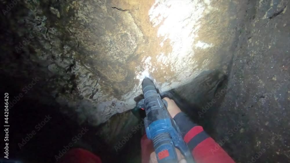 Drilling a hole in a cave with a power tool by a caving explorer. Drilling a hole in a cave with a power tool by a caving explorer.
