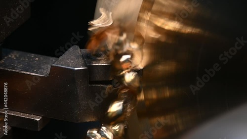 Close-up scene of lathe machine cutting the brass material part with unbroken snarls chip. The metal working process by turning machine.