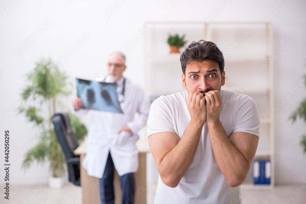 Fototapeta premium Young male patient visiting old male doctor radiologist