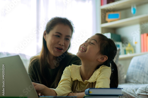 Home study concept : A Beautiful single Asian mother teaching her daughter to read, write and drawing at home