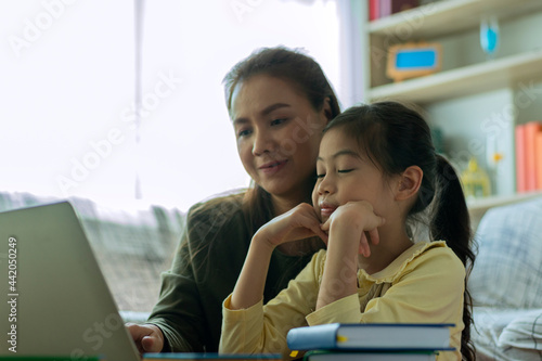 Home study concept : A Beautiful single Asian mother teaching her daughter to read, write and drawing at home
