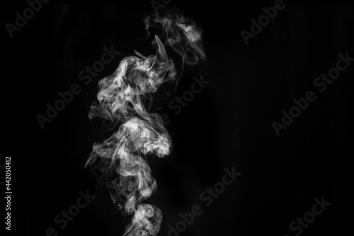 Perfect mystical curly white steam or smoke isolated on black background. Abstract background fog or smog, design element for Halloween, layout for collages.