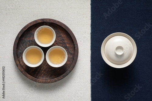 Three cups of tea are placed in a round black walnut wooden tray. Tea art tea seats.