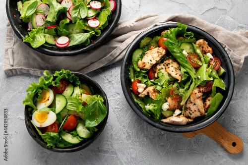 Freshly made salads on light gray background. Seasonal food concept.