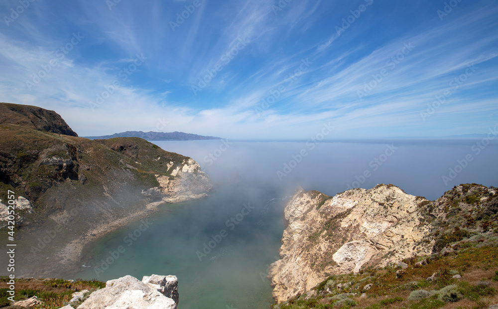Potato Harbor on Santa Cruz Island with foggy mist coming in under blue cirrus sky in the Channel Islands National Park offshore from Santa Barbara California USA