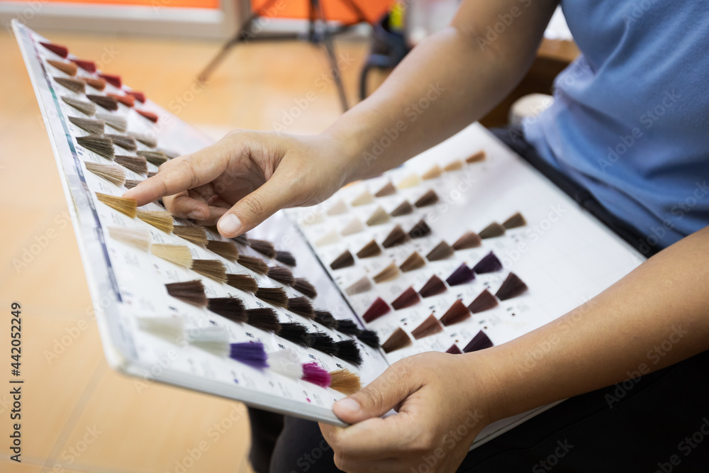 Woman holding hair color swatches and pointing finger selecting at