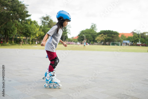 Fotografie smiling 5 year old asian girl going on her in-line skates