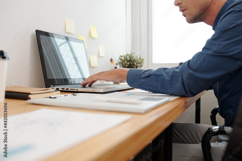 Cropped image of businessman working on laptop at his office desk, he is filling calendar with things to do Cropped image of businessman working on laptop at his office desk, he is filling calendar with things to do