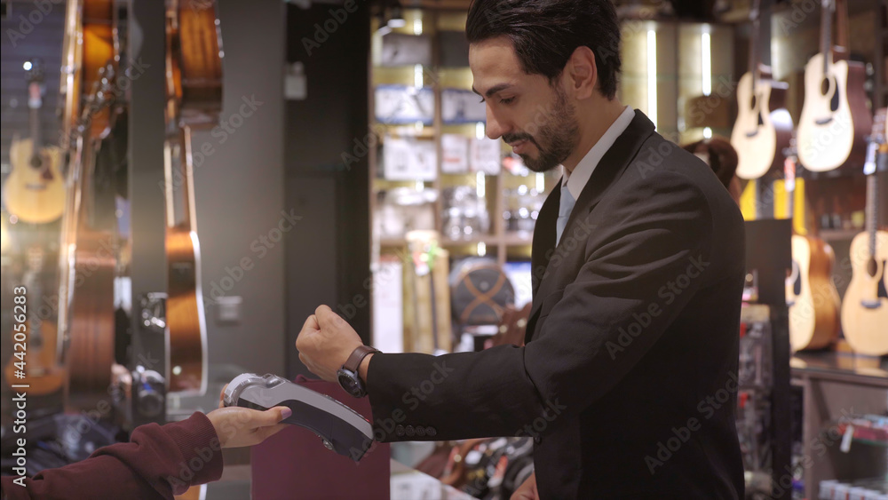 An upwardly mobile Muslim man using smart payment to pay for a product at a sale terminal with nfc identification payment for verification and authentication