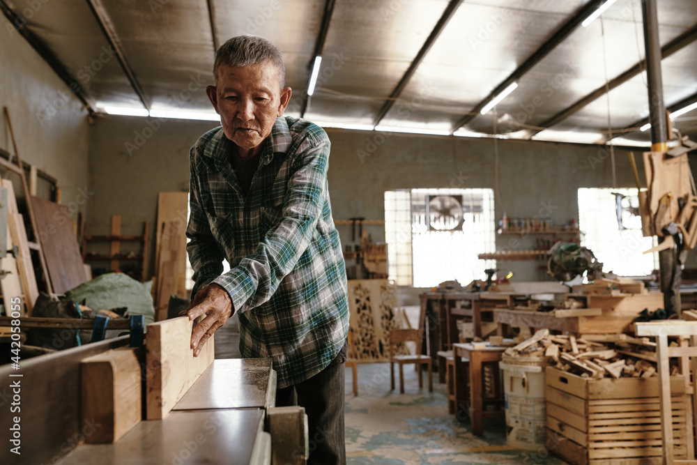 Professional experienced carpenter using bench top jointer to get flat surface along boards length Professional experienced carpenter using bench top jointer to get flat surface along boards length