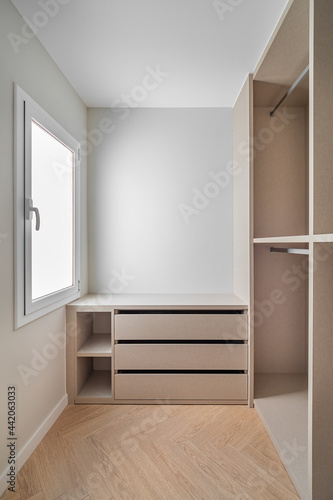 New built-in furniture in a small dressing room. Modern and empty storage room with wardrobe, drawers and plenty of space for hangers.