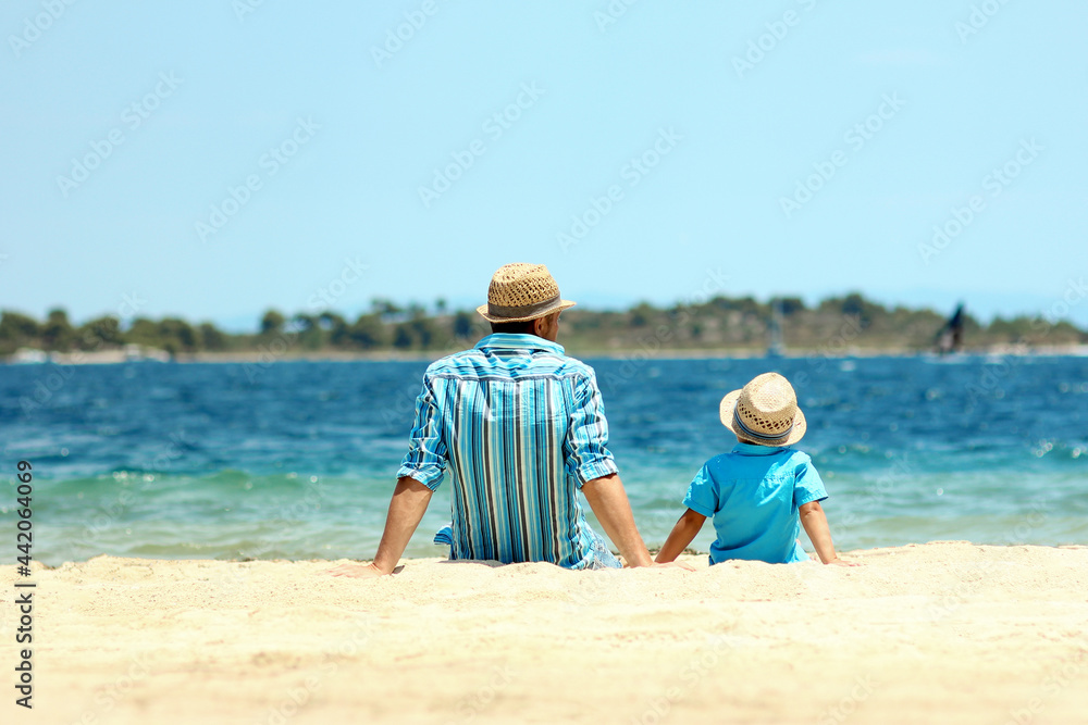 father and son sit by the sea