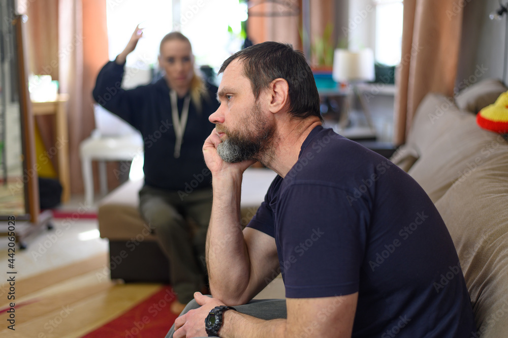 Obraz premium Photo man unhappy listens to the girl in the background on the couch at home