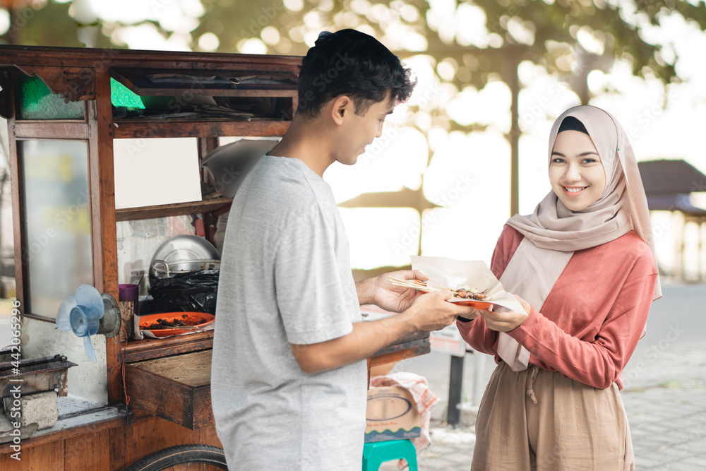 muslim woman ordering chicken satay from small food cart seller. sate ayam street food muslim woman ordering chicken satay from small food cart seller. sate ayam street food