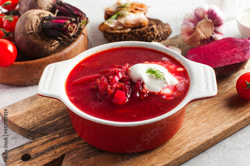 Delicious fresh red borscht, garlic, tomatoes and beets on the kitchen table.