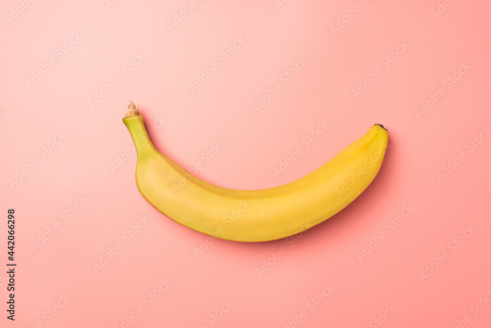 Top view photo of one unpeeled yellow banana in the middle on isolated pastel pink background with blank space Top view photo of one unpeeled yellow banana in the middle on isolated pastel pink background with blank space