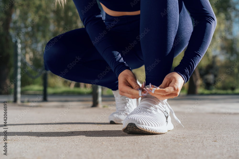Close up of young woman tying laces on her sports shoes