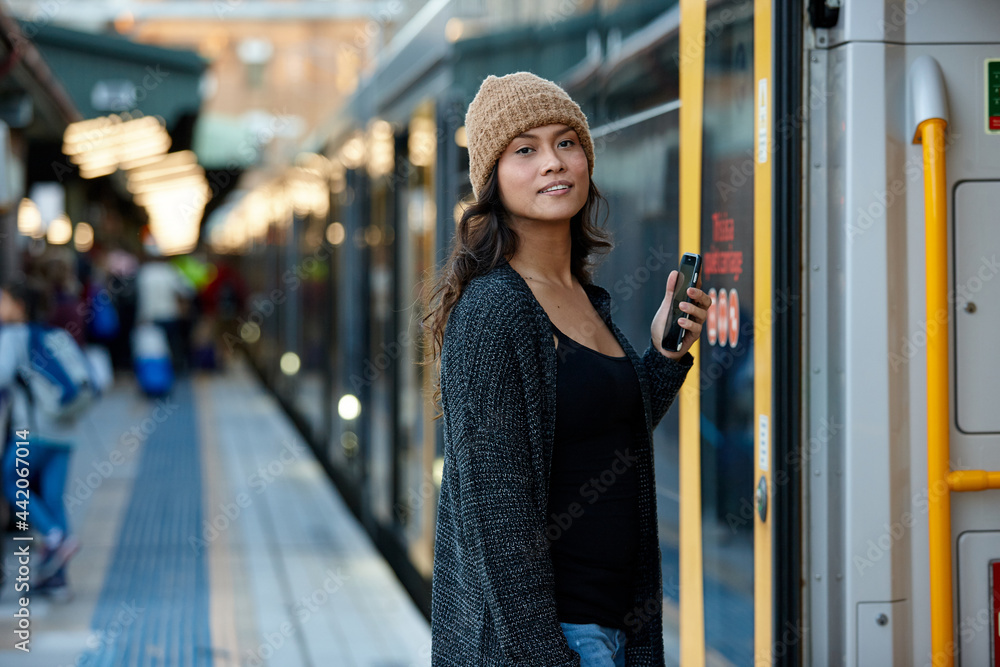 Asian woman getting on train with mobile phone Asian woman getting on train with mobile phone