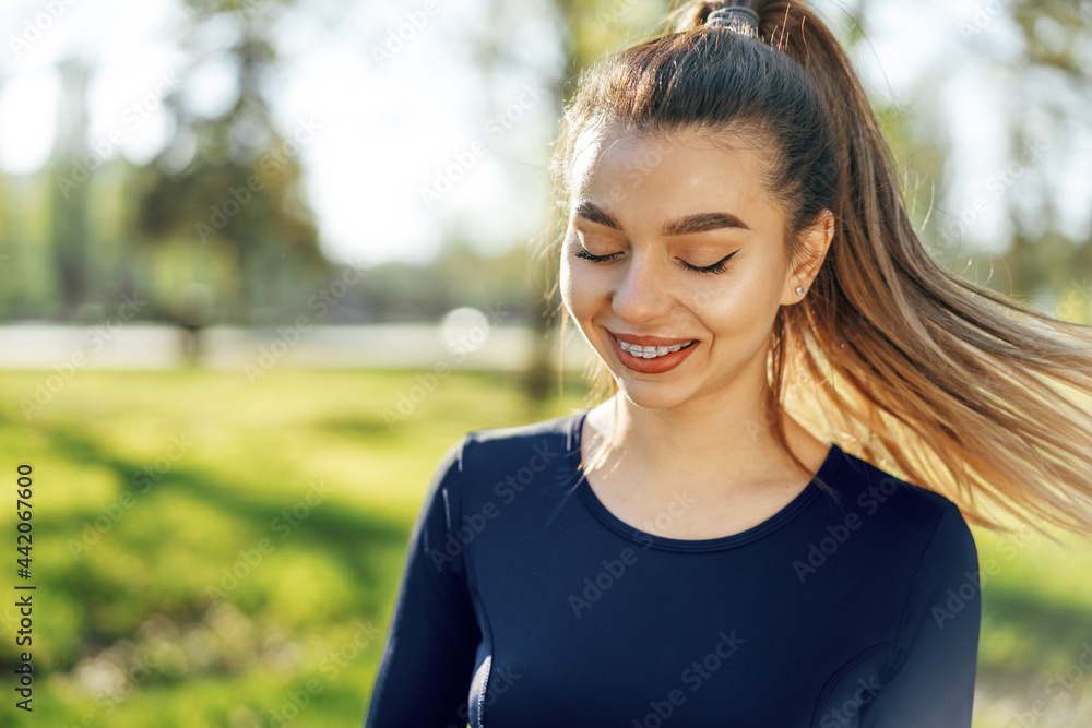 Portrait of a young smiling woman wearing sportswear in morning park