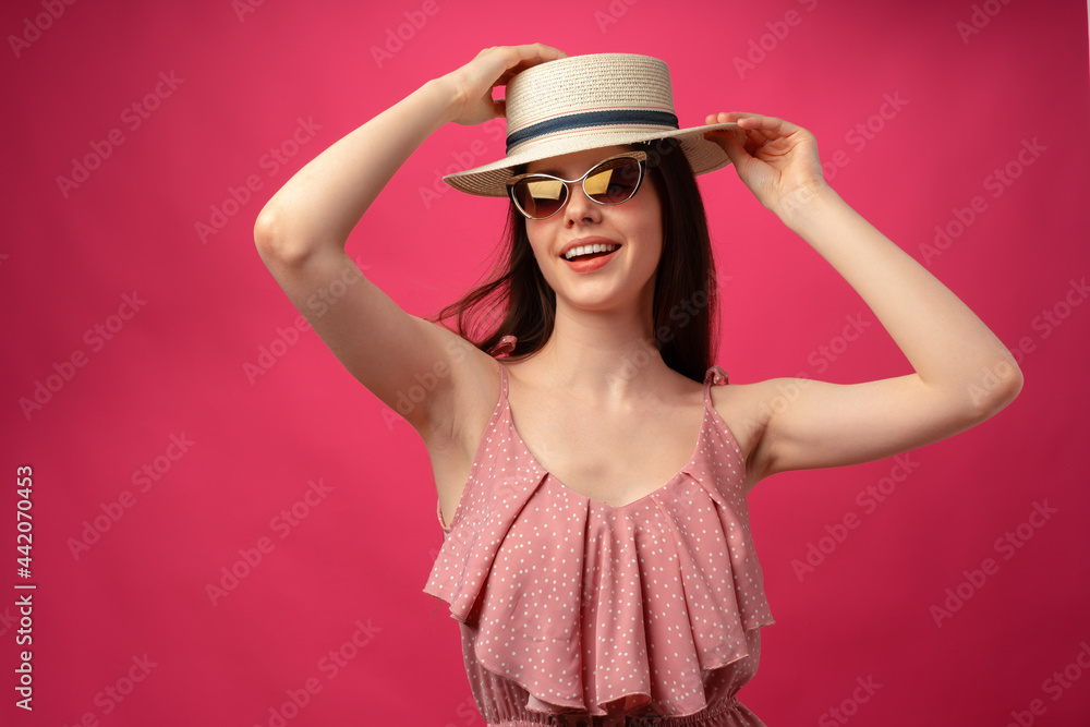 Studio fashion portrait of a young attractive woman in hat and glasses against pink backgorund Studio fashion portrait of a young attractive woman in hat and glasses against pink backgorund
