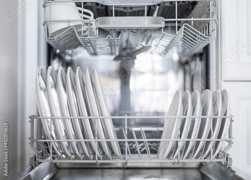 White flat plates are loaded into the dishwasher