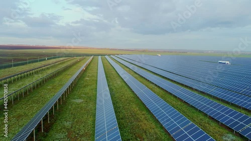 Solar panels at a suburban solar power plant. Farm fields on the background. Silicon photovoltaic cells in polycrystalline solar modules. High quality. 4k footage. photo