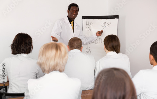 Smiling cheerful positive glad African American male professor giving presentation for medics in lecture hall