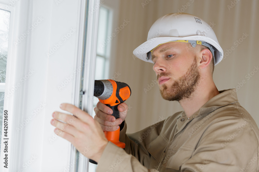 construction worker using drill to install window construction worker using drill to install window