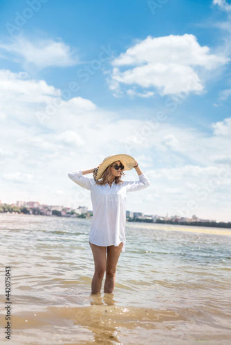 woman in white blouse and straw hat resting on a hot summer day walking on lake