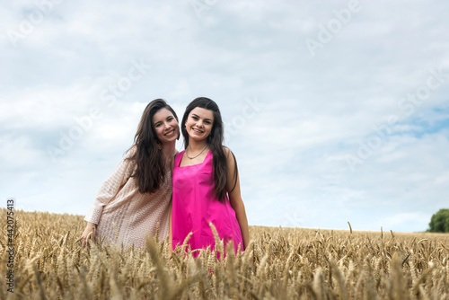 two women in beauty dress possing at wheat field
