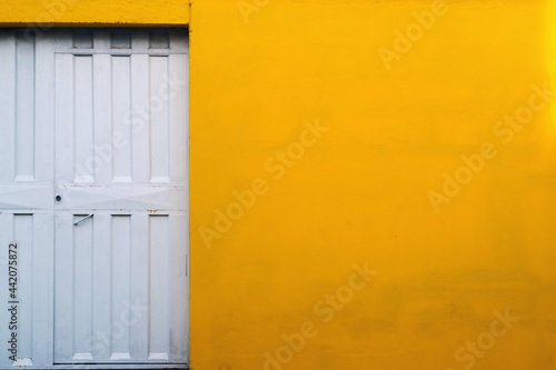 White gate door against a yellow wall.