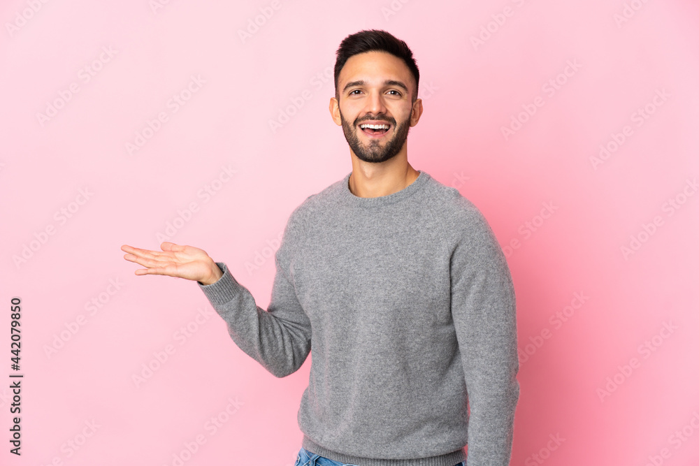 Young caucasian man isolated on pink background presenting an idea while looking smiling towards Young caucasian man isolated on pink background presenting an idea while looking smiling towards
