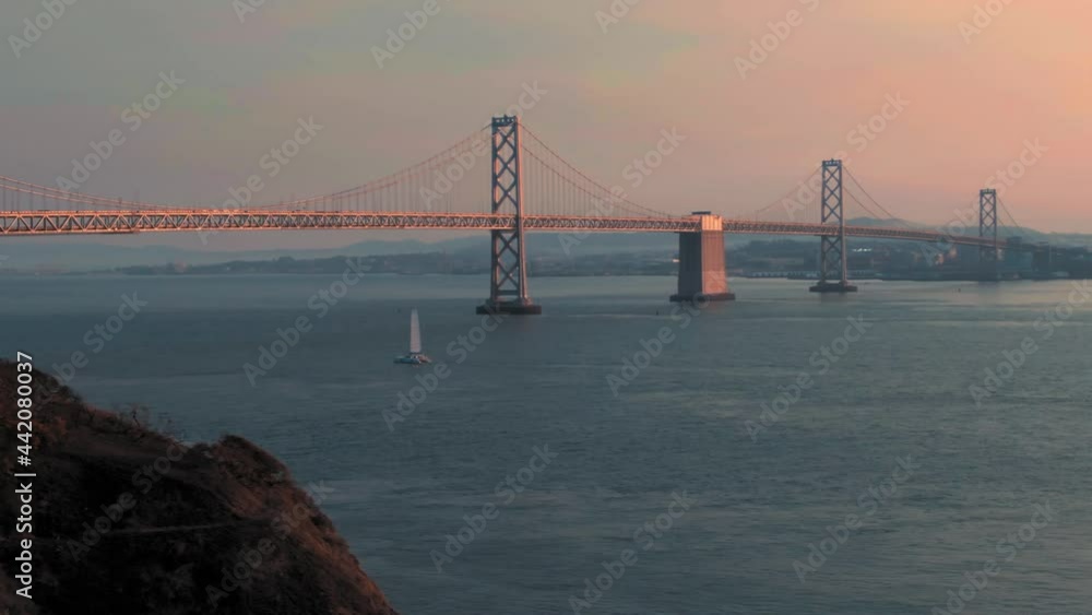 Aerial: San Francisco Bay Bridge, boat sailing in the harbor and Treasure Island at sunrise. California, USA Aerial: San Francisco Bay Bridge, boat sailing in the harbor and Treasure Island at sunrise. California, USA