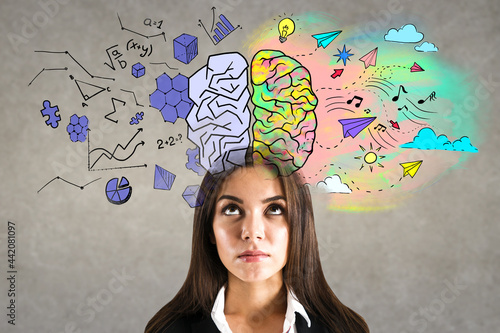 Portrait of attractive young european businesswoman with creative colorful brain sketch on wall background. Brainstorm and hemispheres concept.