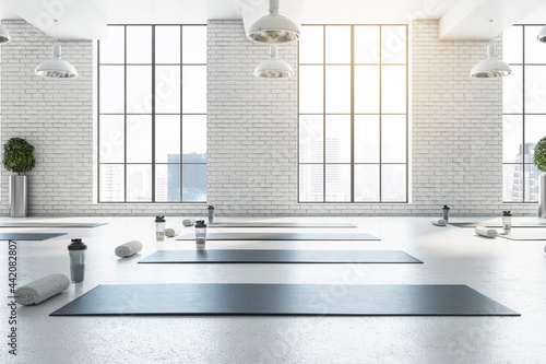 Stylish bright white yoga studio gym interior with brick wall, window and city view. 3D Rendering. photo