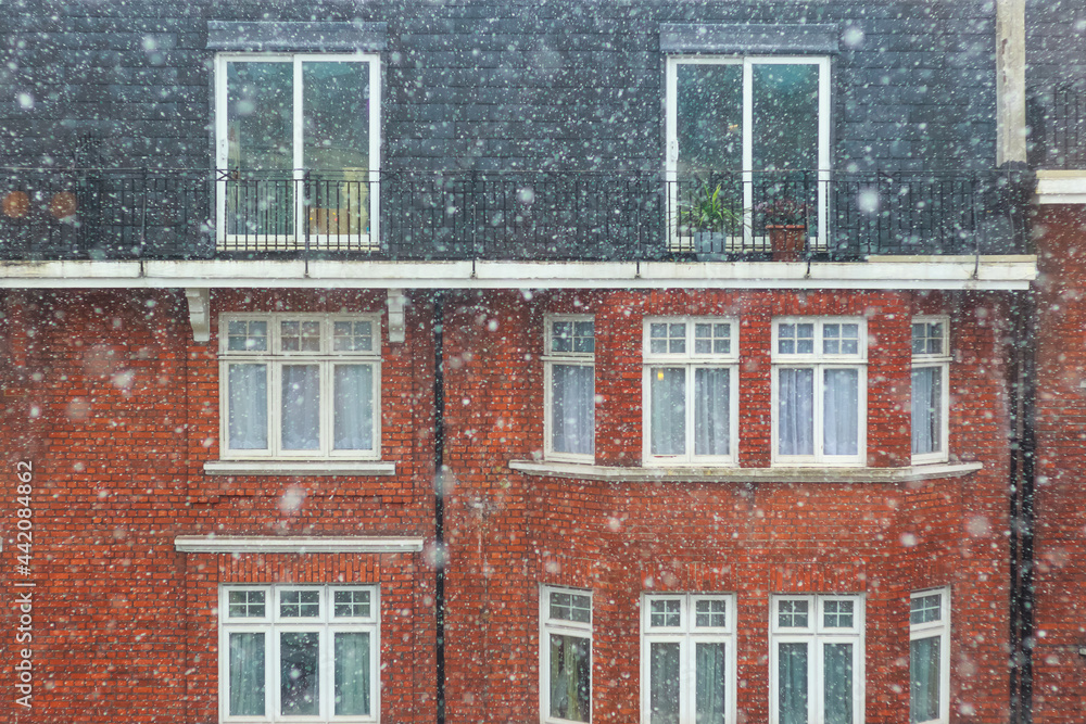 Heavy snow falling in winter with a brick mansion in the background in London