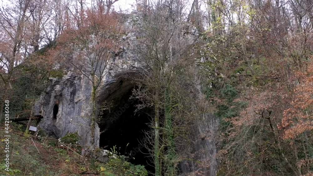 Flying above a monumental cave entrance among trees by drone Flying above a monumental cave entrance among trees by drone