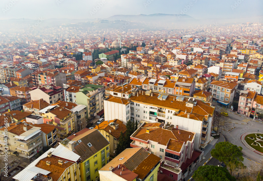 Fototapeta premium Aerial view of Balikesir cityscape with similar brownish tiled roofs on residential buildings in foggy winter day, Turkey.