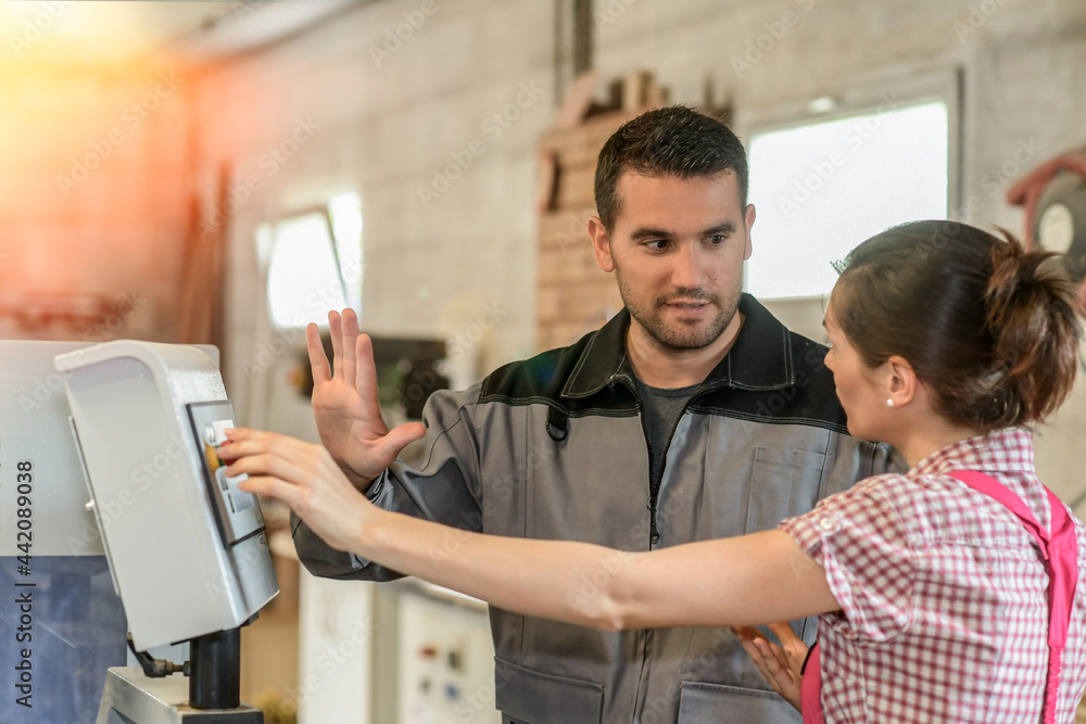 Fototapeta premium Male worker teaching female apprentice how to operate a machine