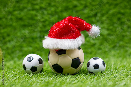 Soccer ball with Christmas Decoration on green grass background for Holiday