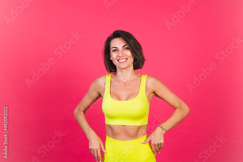 Beautiful fit woman in yellow bright fitting sportswear on pink background happy moving excited perfect body fitness motivation