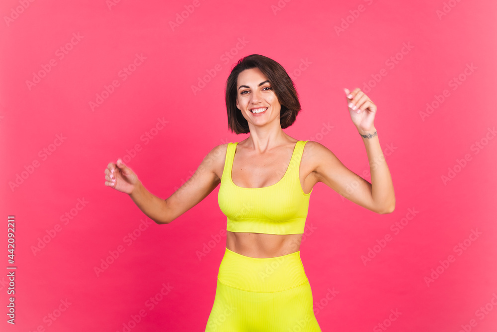 Beautiful fit woman in yellow bright fitting sportswear on pink background happy moving excited perfect body fitness motivation Beautiful fit woman in yellow bright fitting sportswear on pink background happy moving excited perfect body fitness motivation