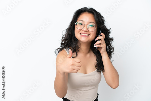 Young asian woman isolated on white background using mobile phone while doing thumbs up