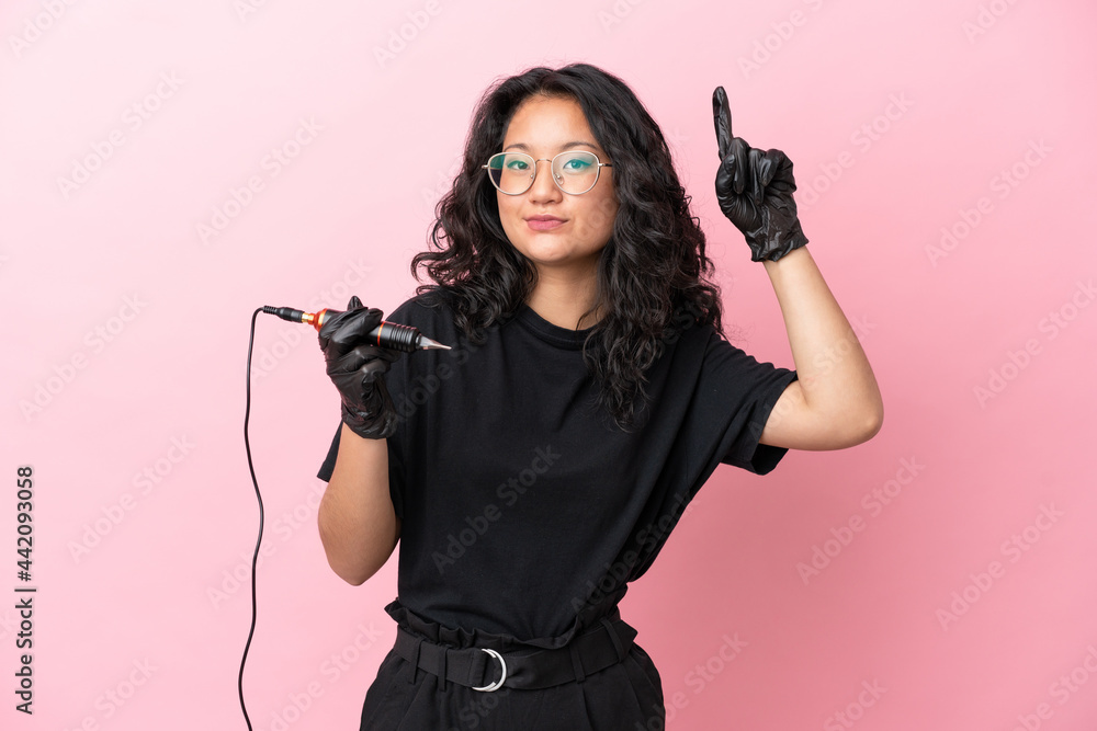 Tattoo artist asian woman isolated on pink background pointing up a great idea