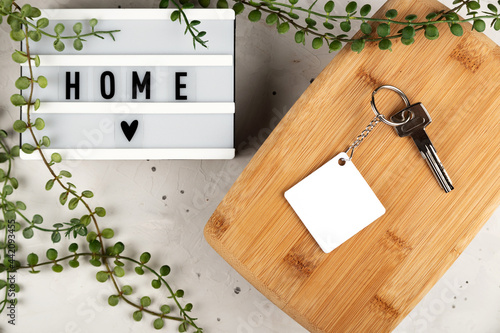 Blank rhombus white sublimation keychain mockup next to board with home inscription. Key chain mockup to display design. photo